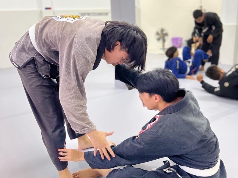 Beginners learning a Brazilian Jiu-Jitsu escape during a fundamentals class in Chiang Mai