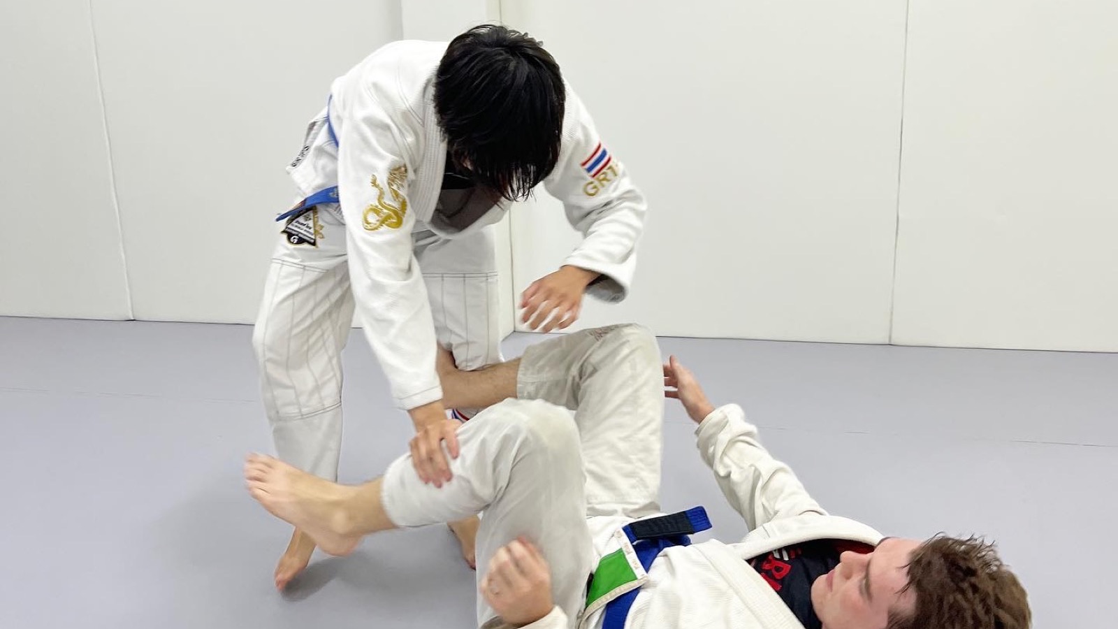 Students rolling in pairs during a Brazilian Jiu-Jitsu class at Gato Studio BJJ in Chiang Mai